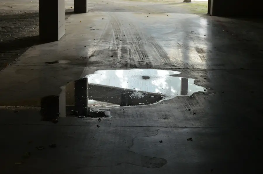 Puddle of water spreading across a dark concrete floor