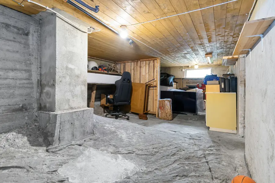 Unfinished basement with a concrete floor, a timber ceiling and stored furniture
