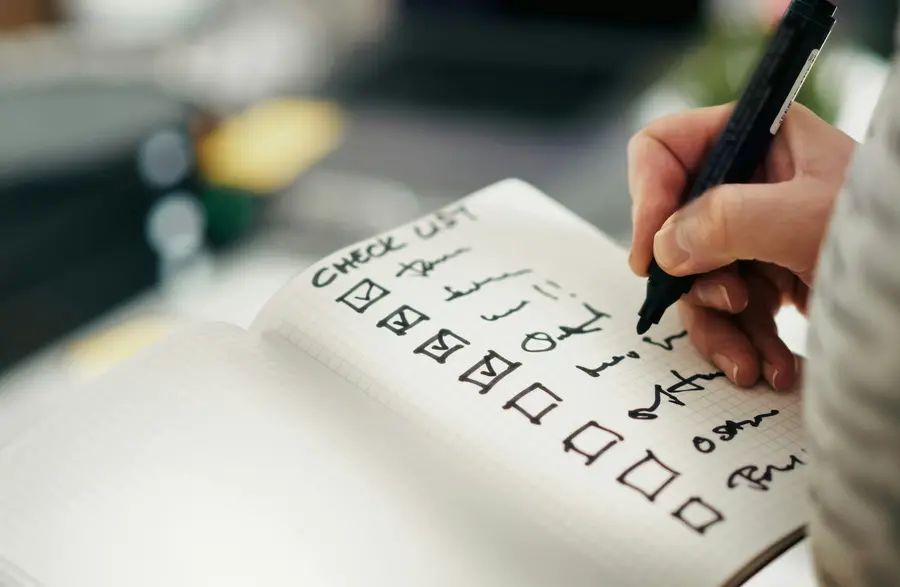 Hand ticking boxes on a handwritten checklist with a black pen