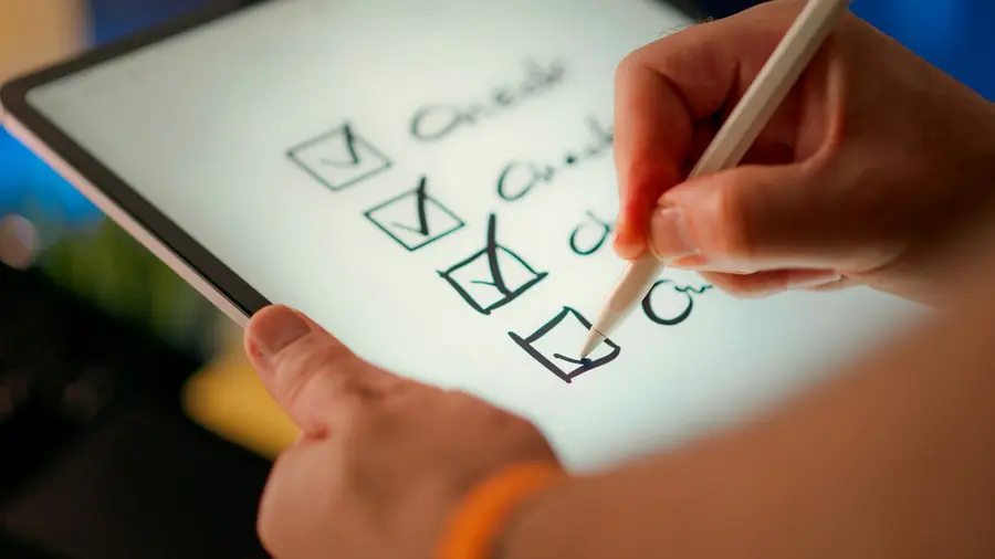 Hand ticking boxes on a checklist on a tablet with a stylus