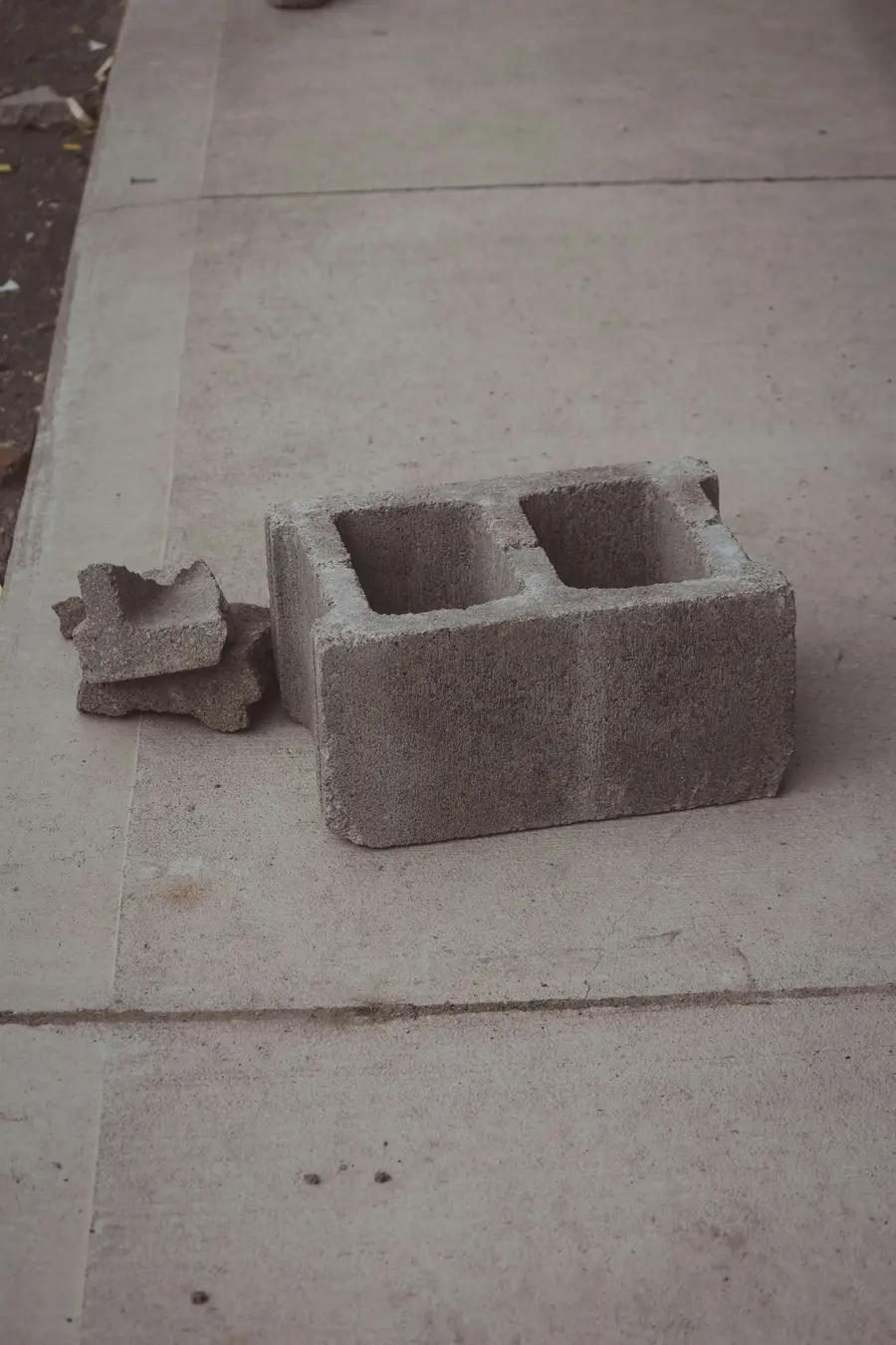 A single grey concrete block beside a broken piece of block
