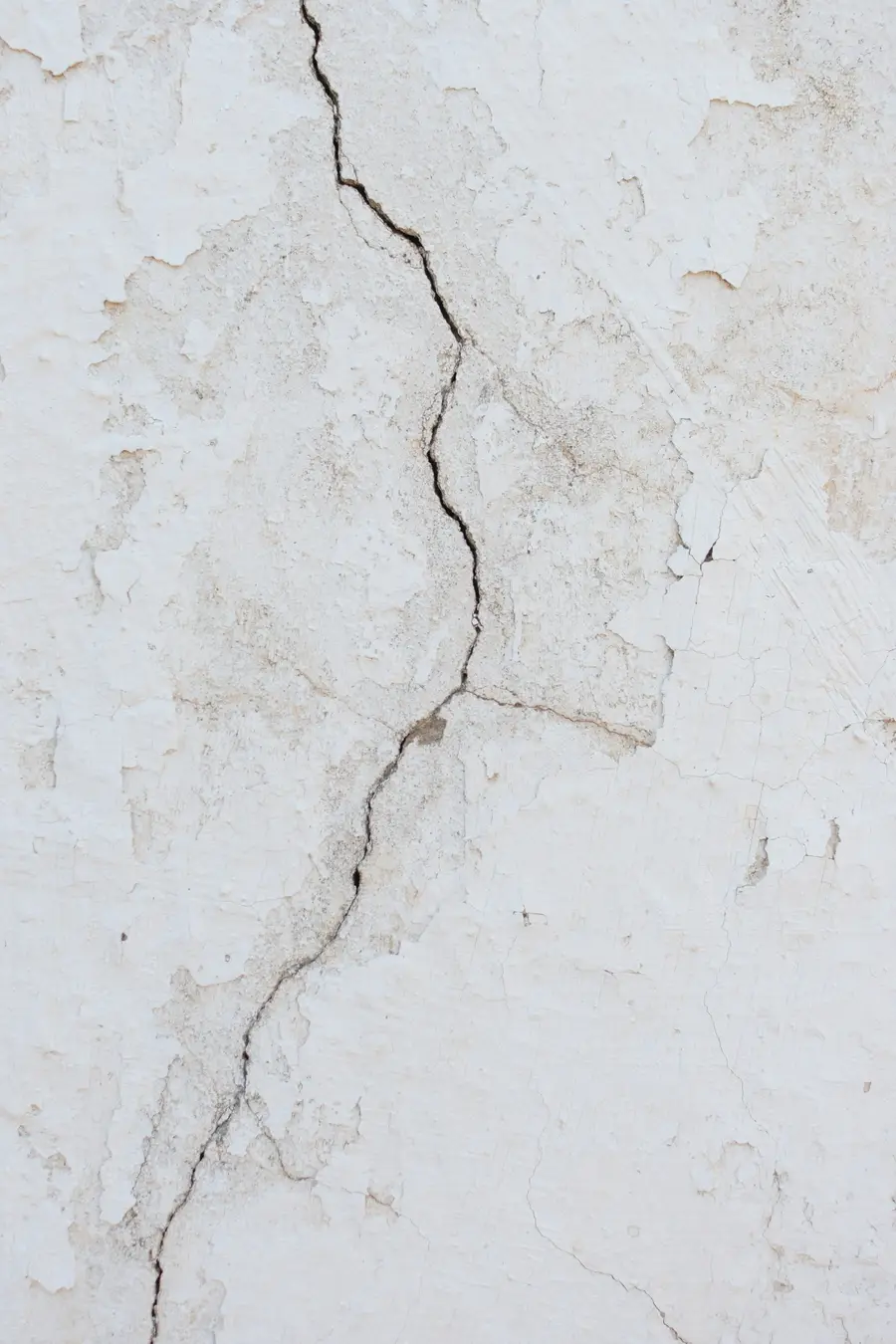 Forked crack running through white plaster on a wall