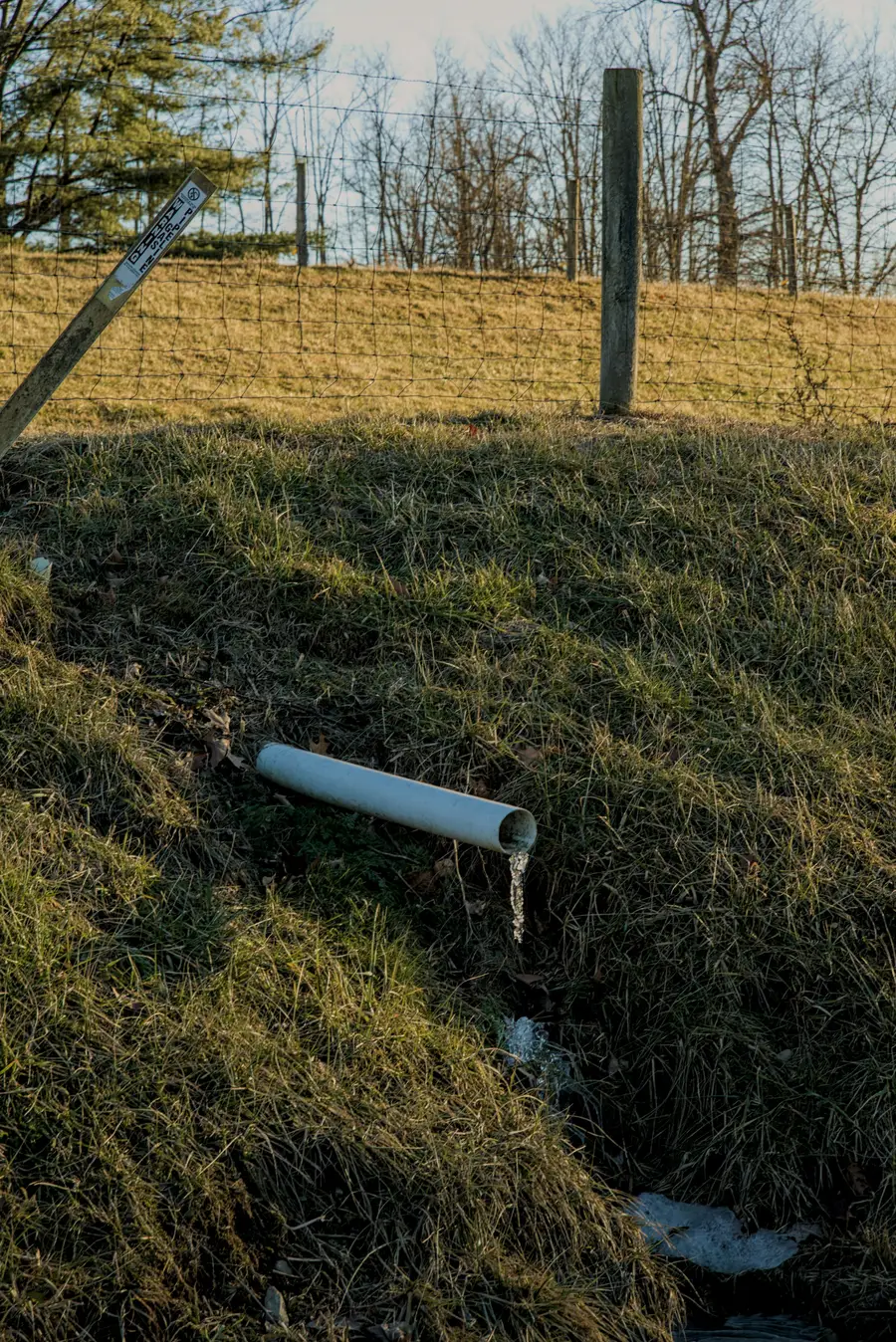 White plastic discharge pipe ending on a grassy slope