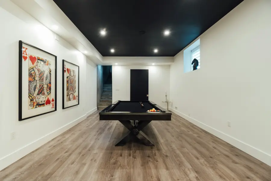 Finished basement with a pool table, pot lights and a wood-look floor