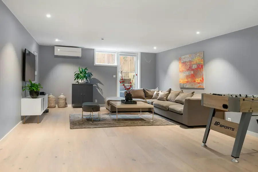 Finished basement living room with a sectional sofa and a games table