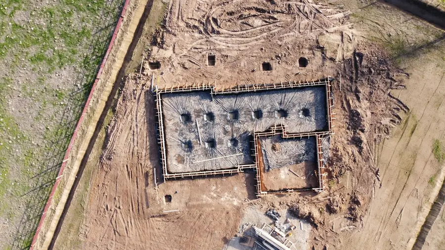 Aerial view of concrete footings and foundation walls being built in an open field