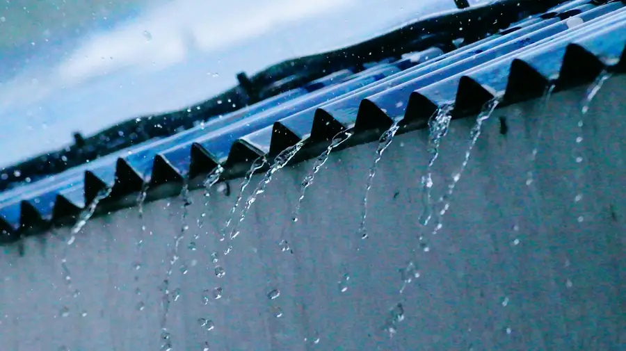 Rainwater pouring over the edge of an eavestrough during a storm