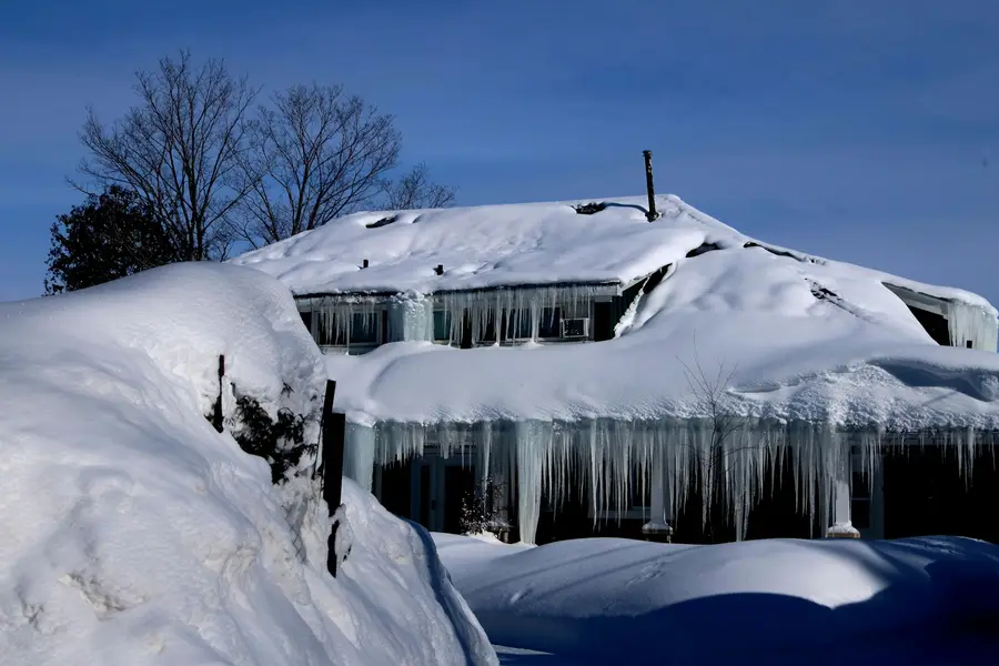 Long icicles hanging from a snow-covered roof edge