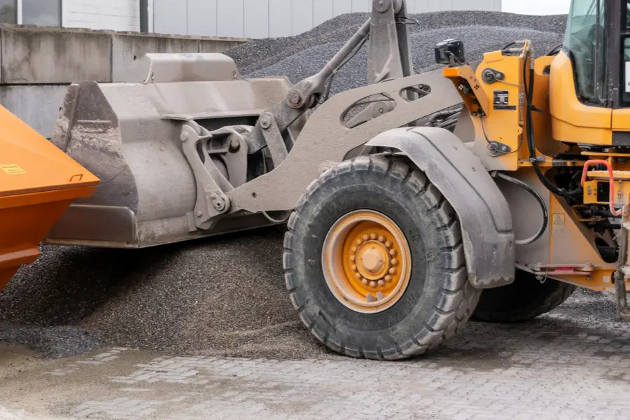 Wheel loader with its bucket in a pile of grey gravel