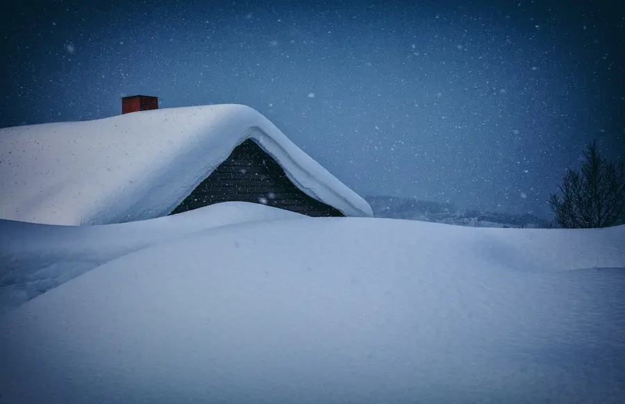 Deep snow on the roof of a house at night