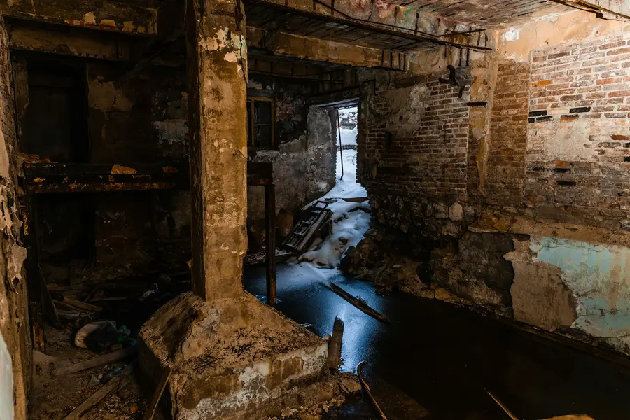 Dark old basement with brick and stone walls and water standing on the floor