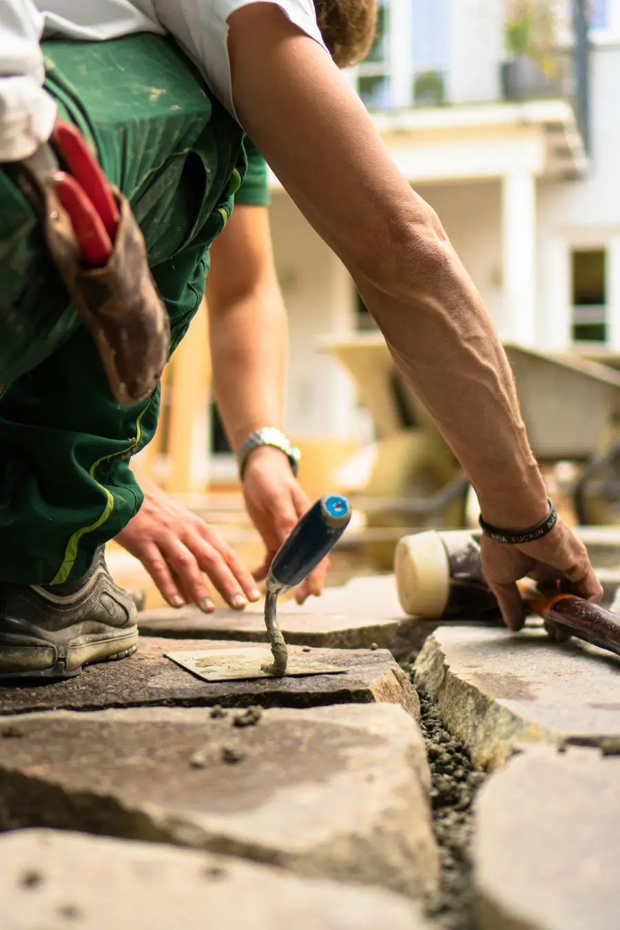 Worker pressing mortar into a joint between stone slabs with a pointing trowel