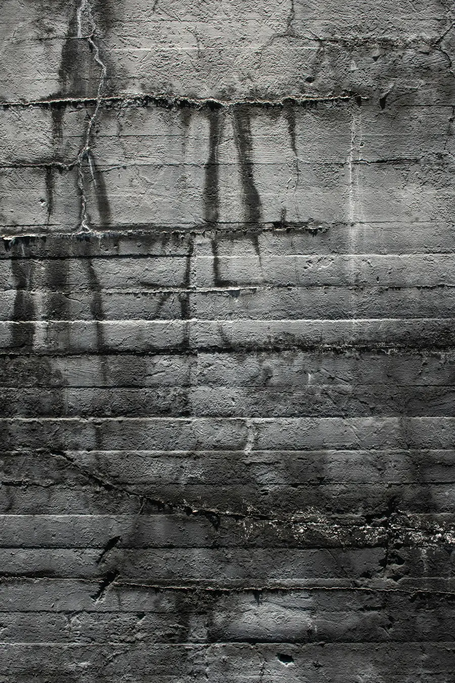 Dark water stains and streaks on a bare concrete basement wall